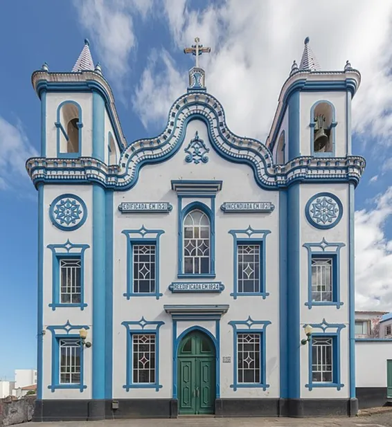 La fachada principal de esta capilla con detalles azules en los bordes, dos torres a los lados y la corona arriba