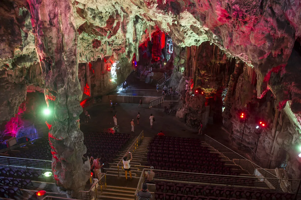 Interior de la cueva de st. Michael iluminada con luz roja y gente visitandola