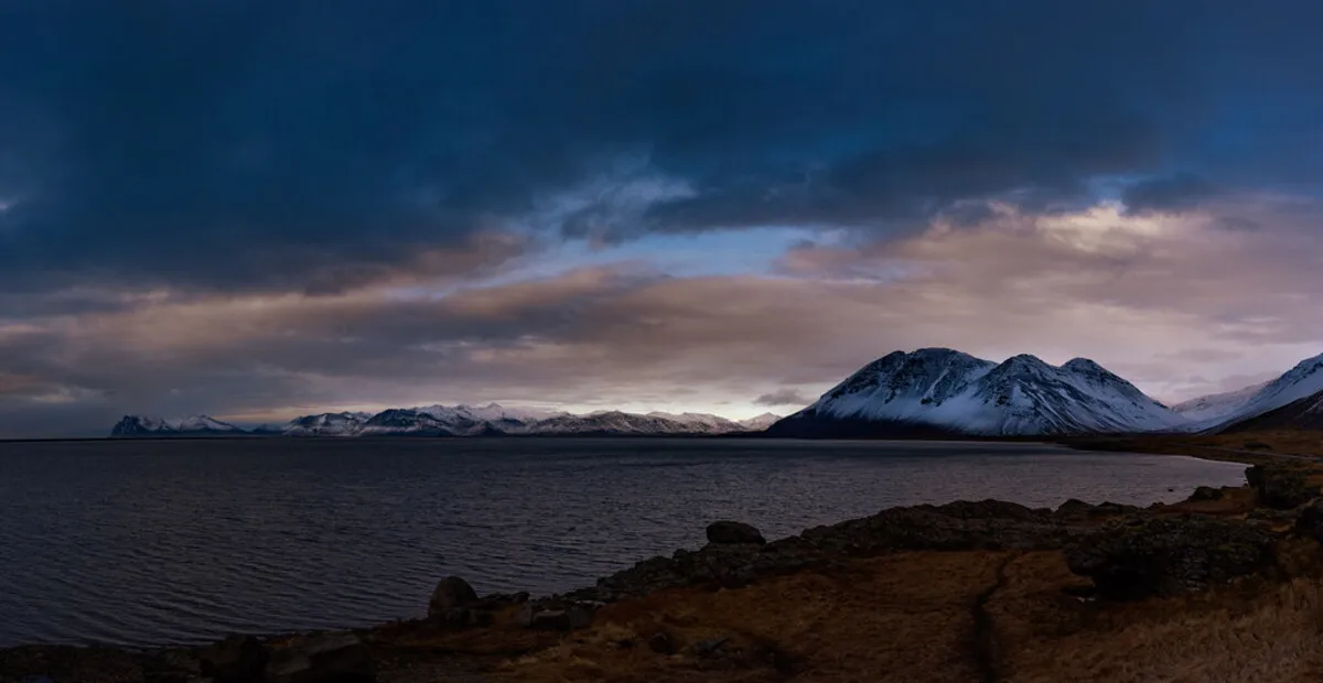 Panorámica de la montaña nevada al fondo durante un atardecer nublado