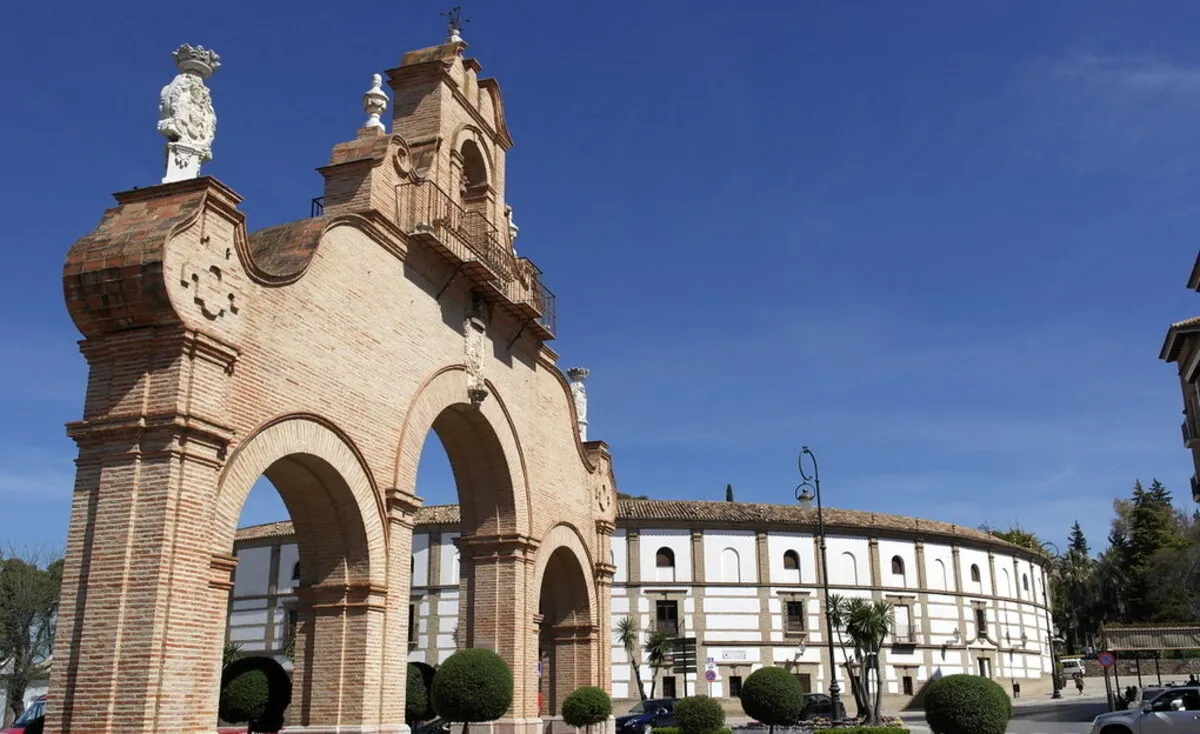 La famosa plaza de toros de Antequera de color blanco y tres arcos de piedra delante