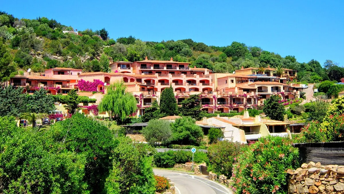 Los apartamentos turísticos de Costa Esmeralda con fachada naranja y flores en los balcones