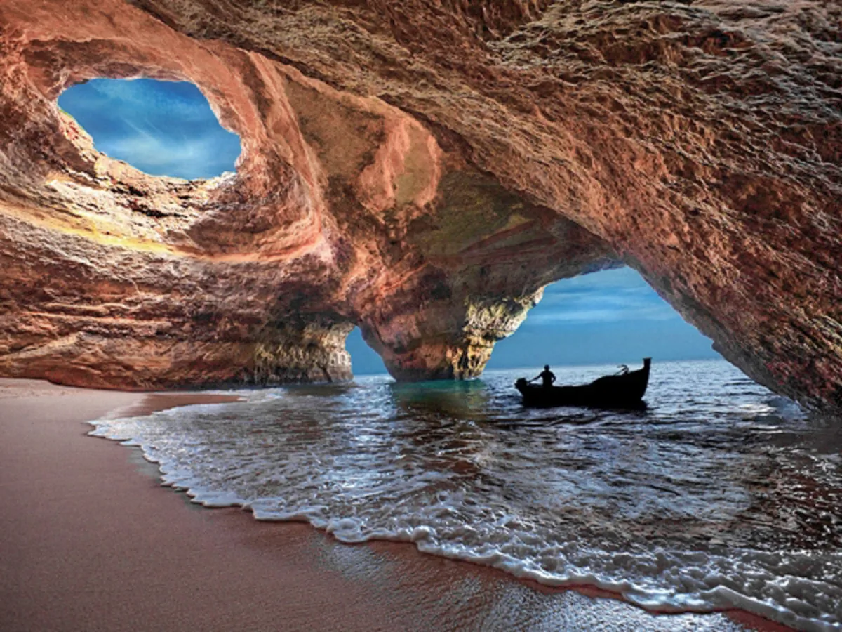 El interior de la cueva con la luz del sol entrando por el circulo de la parte superior y una barca anclada en orilla