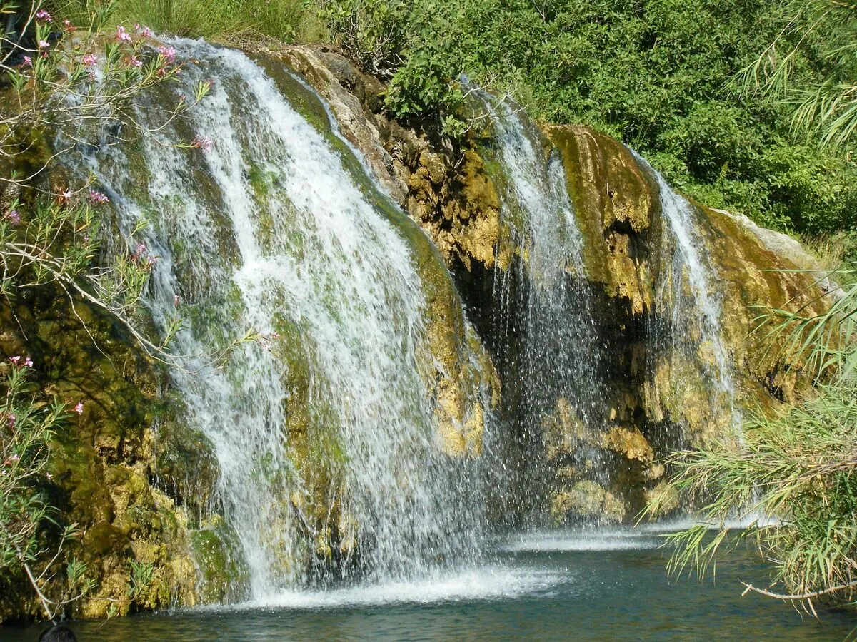 Una de las cascadas desembocando en un lago con el agua cristalina y rodeado de vegetación.