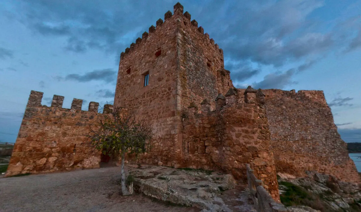 Foto en picado del castillo medieval con fuertes muros de piedra mientras anochece