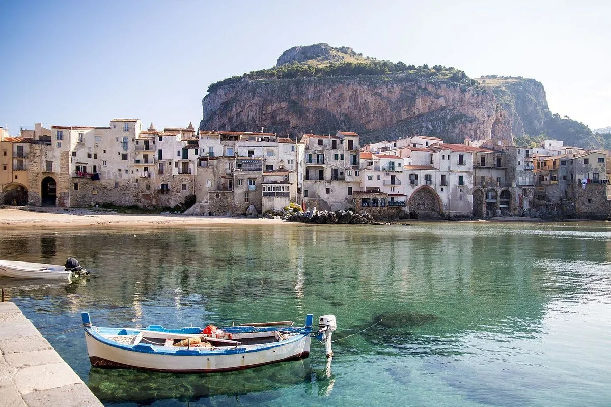 Panorámica del pueblo de Cefalù con las casas estilo arquitectónico medieval en la orilla de la playa y una barca