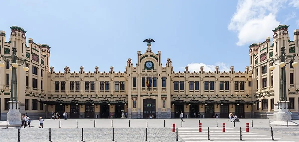 La fachada principal de la estación, con un águila sobre la puerta principal y la plaza con gente paseando