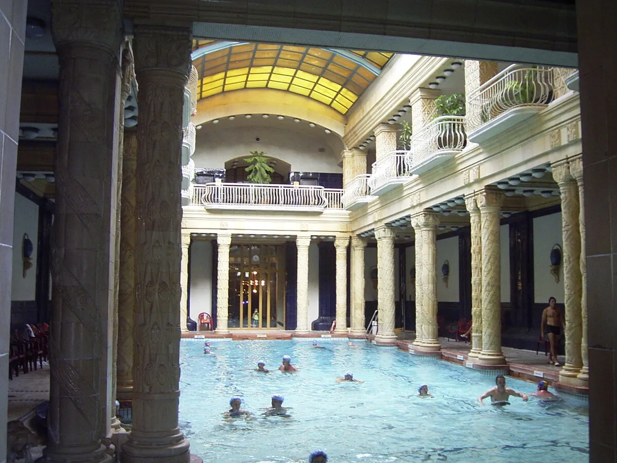 El interior del balneario con varias personas bañandose en la piscina principal
