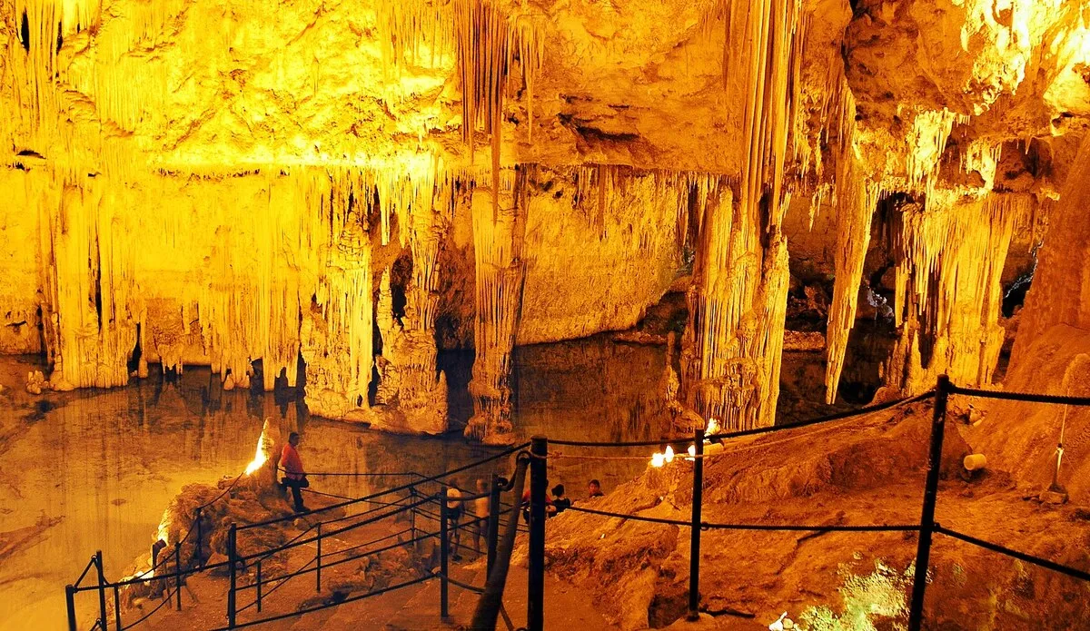 Interior de la cueva con estalactitas y estalactitas, iluminadas con una luz naranja