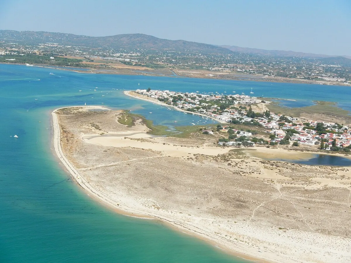 Una panoramica desde el cielo de la isla y de la costa portuguesa, con veleros en el mar y casas en una parte de la isla