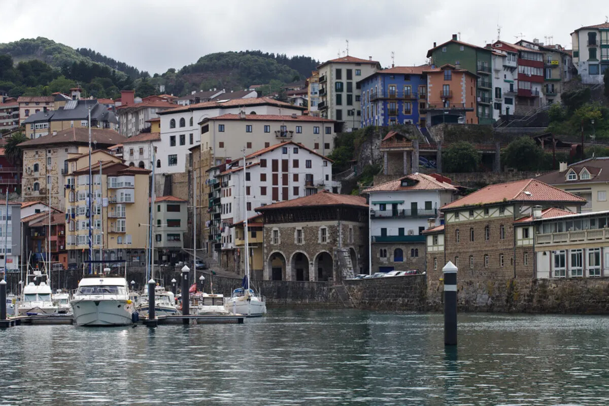 Panoramica del puerto de piedra con los barcos pesqueros anclados y las casas de colores de fondo