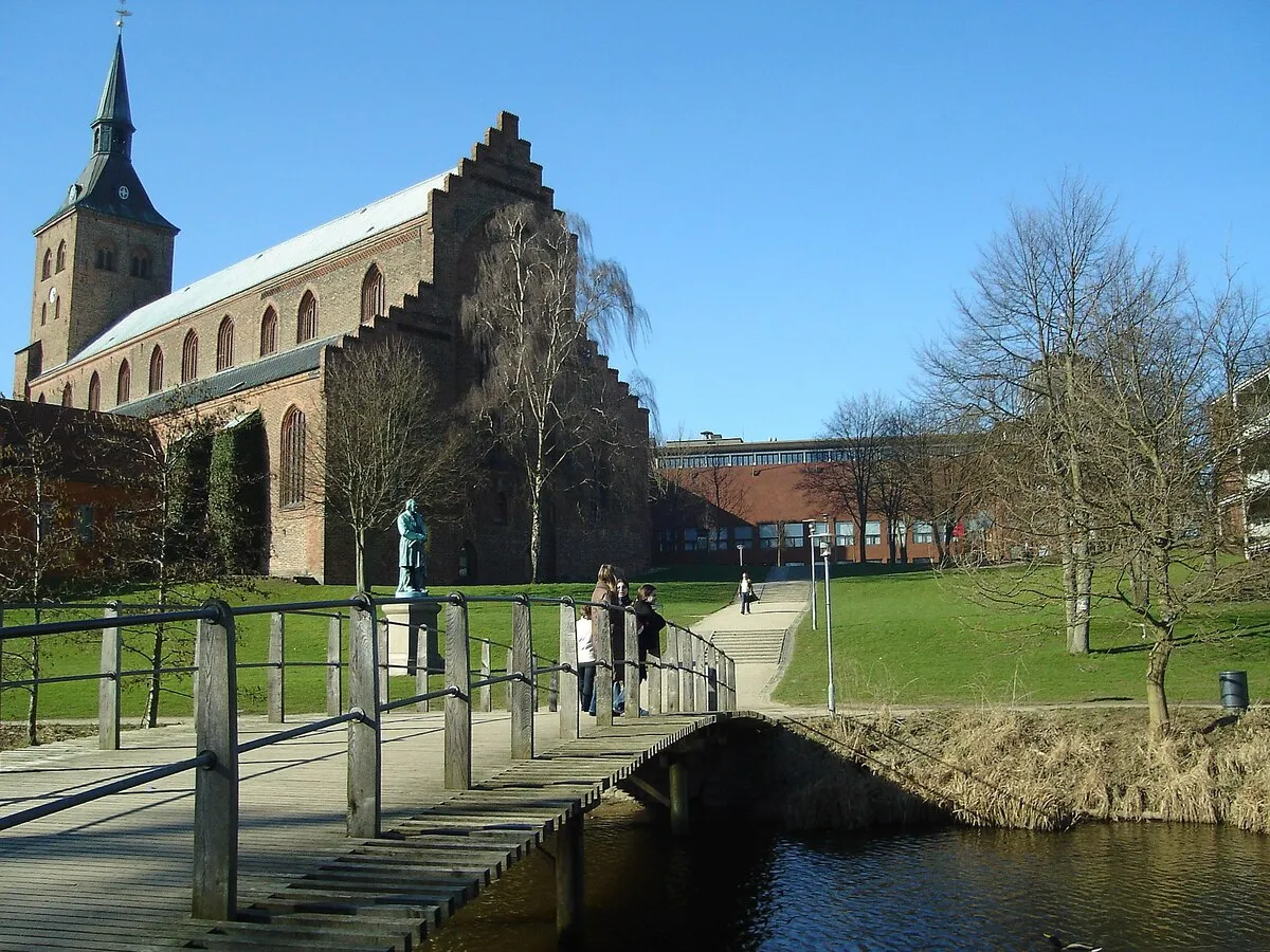 Un puente de madera que cruza el parque de Andersen Haven y la parte de atrás de la catedral de San Canuto