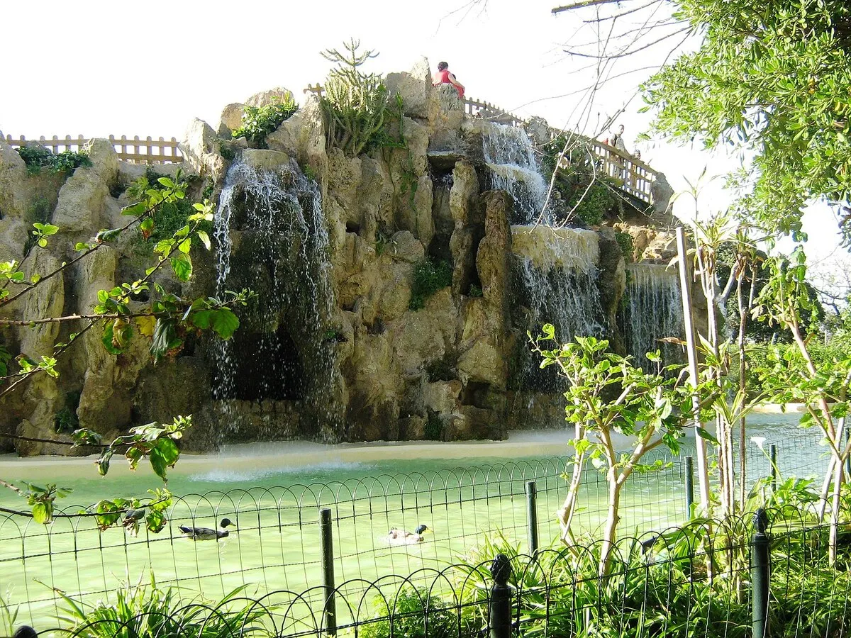 El lago con patos que hay en el parque con agua cayendo de las rocas