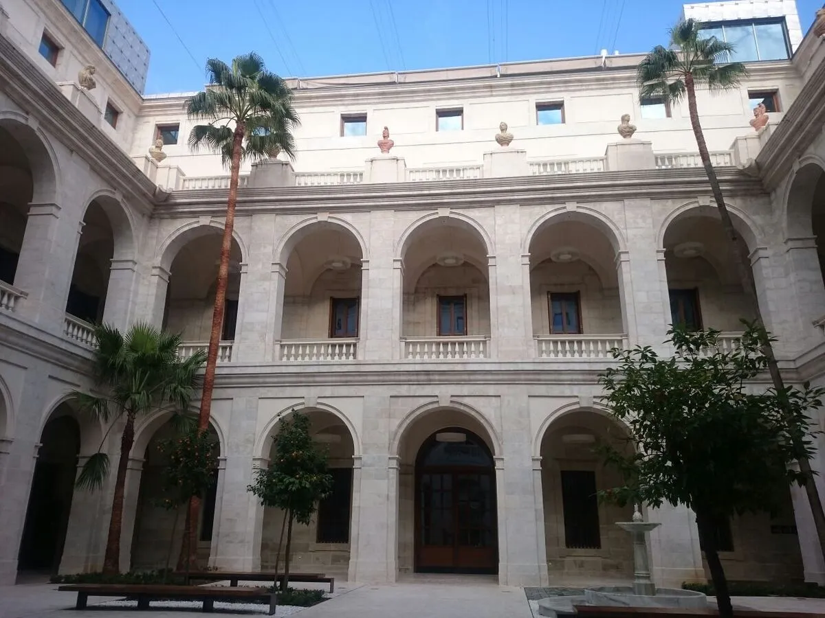 Patio del palacio con palmeras, balcones de mármol y arcos