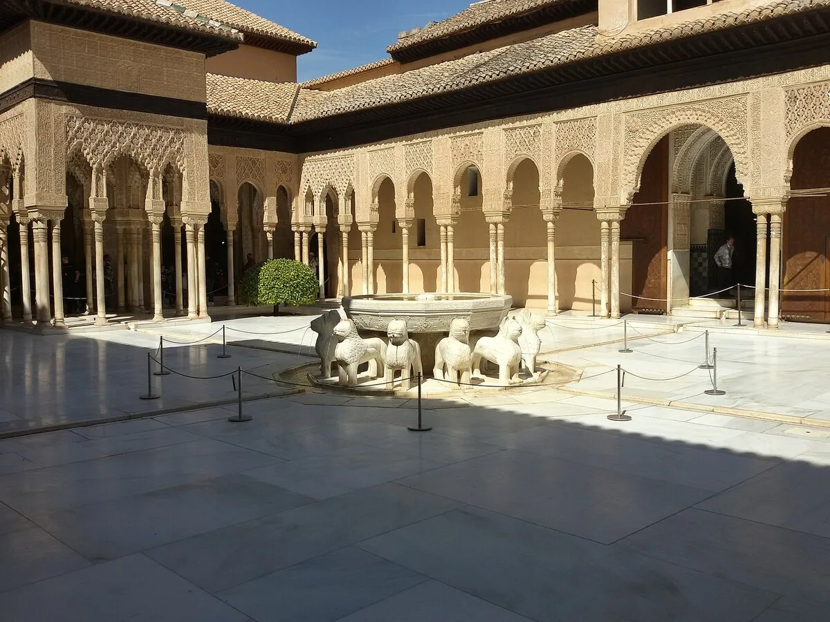 El patio de los leones con la fuente en el centro y los arcos Nazaríes al fondo durante un día soleado