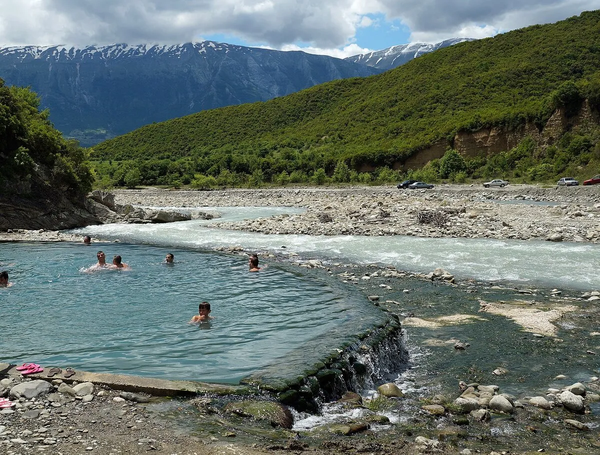 Una de las termas con gente bañándose y las montañas de fondo