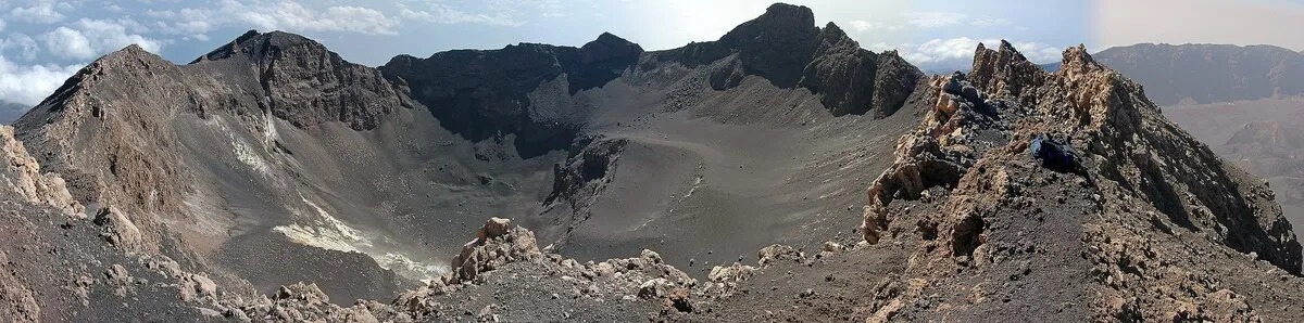 El pico de la montaña dentro de un cráter con arena volcánica y todo terreno árido color gris