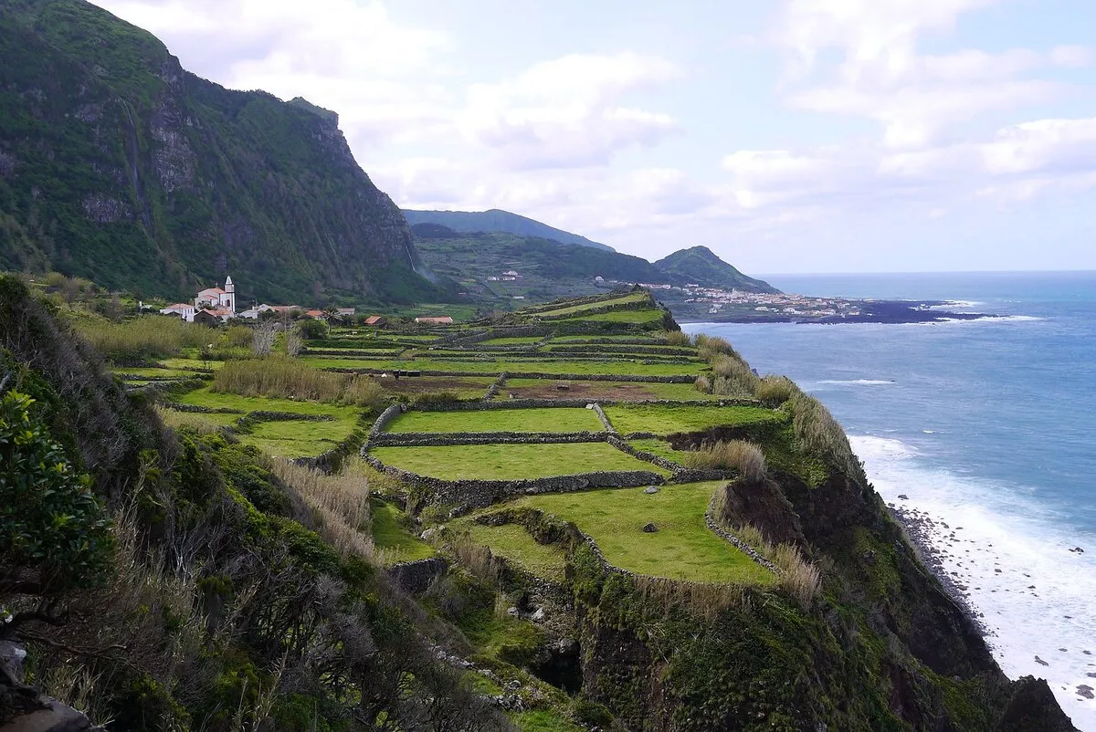 El pequeño pueblo Ponta da Faja desde el sendero, al lado de los acantilados y el océano.
