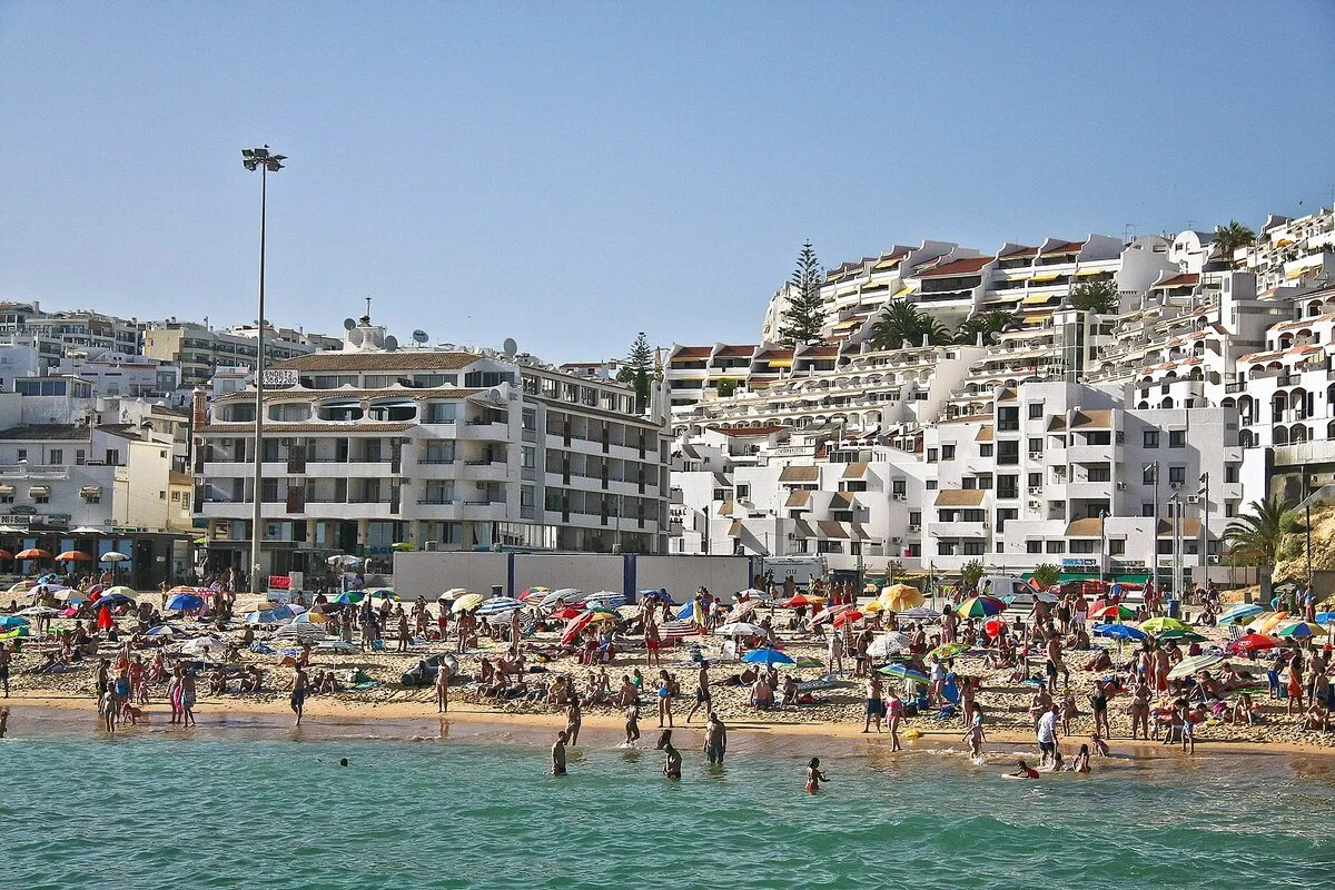 La playa con mucha gente y los edificios blancos del centro de Albufeira de fondo