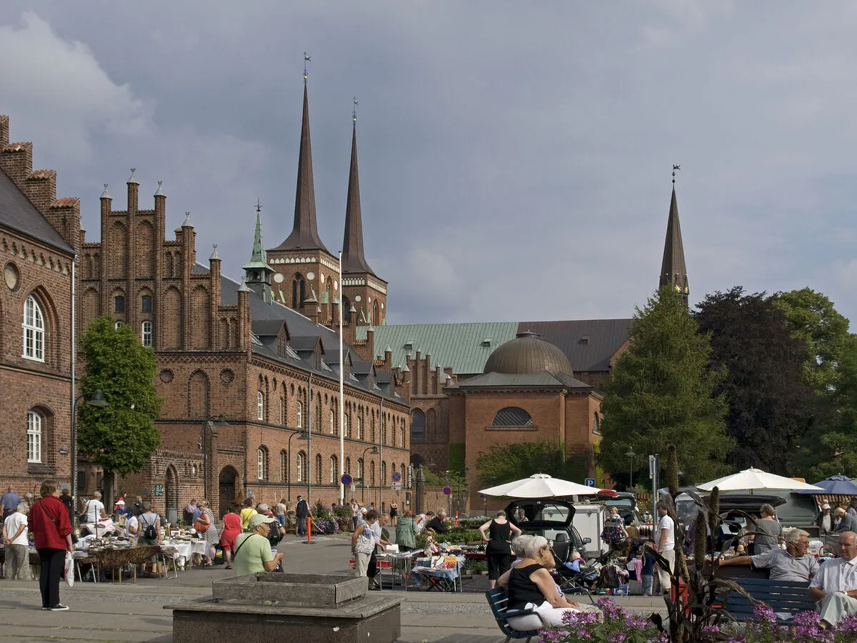 Una de las calles principales de Roskilde llena de gente y terrazas con la catedral de fondo