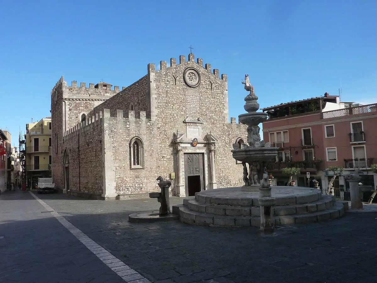 La entrada principal a la catedral fortificada con un pequeño rosetón en la parte superior, junto a una preciosa fuente
