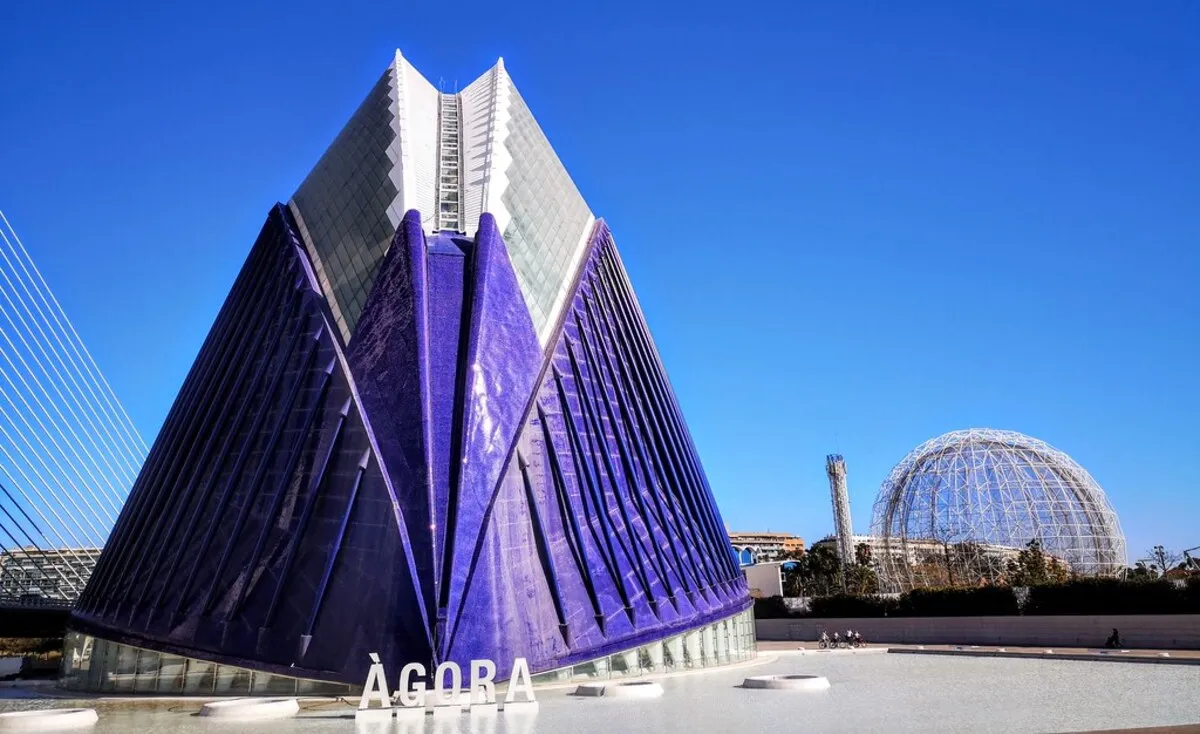 El edificio azul de frente en medio de la plaza blanca donde se encuentra