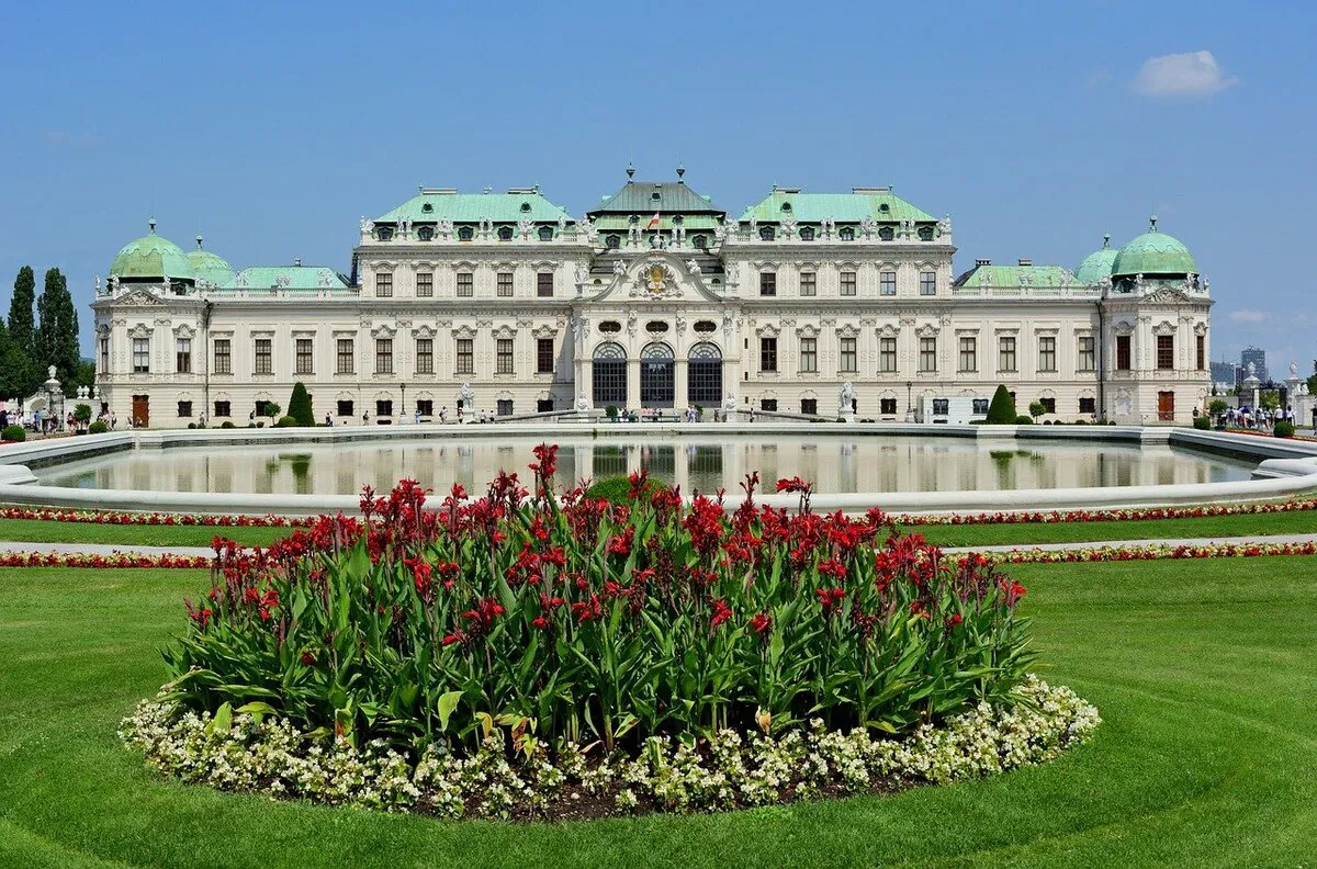 La parte trasera del Palacio Belvedere con unas flores rosas y una preciosa fuente.