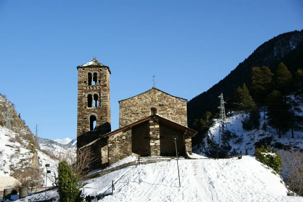 Entrada principal de la iglesia de piedra de Canillo rodeada de nieve