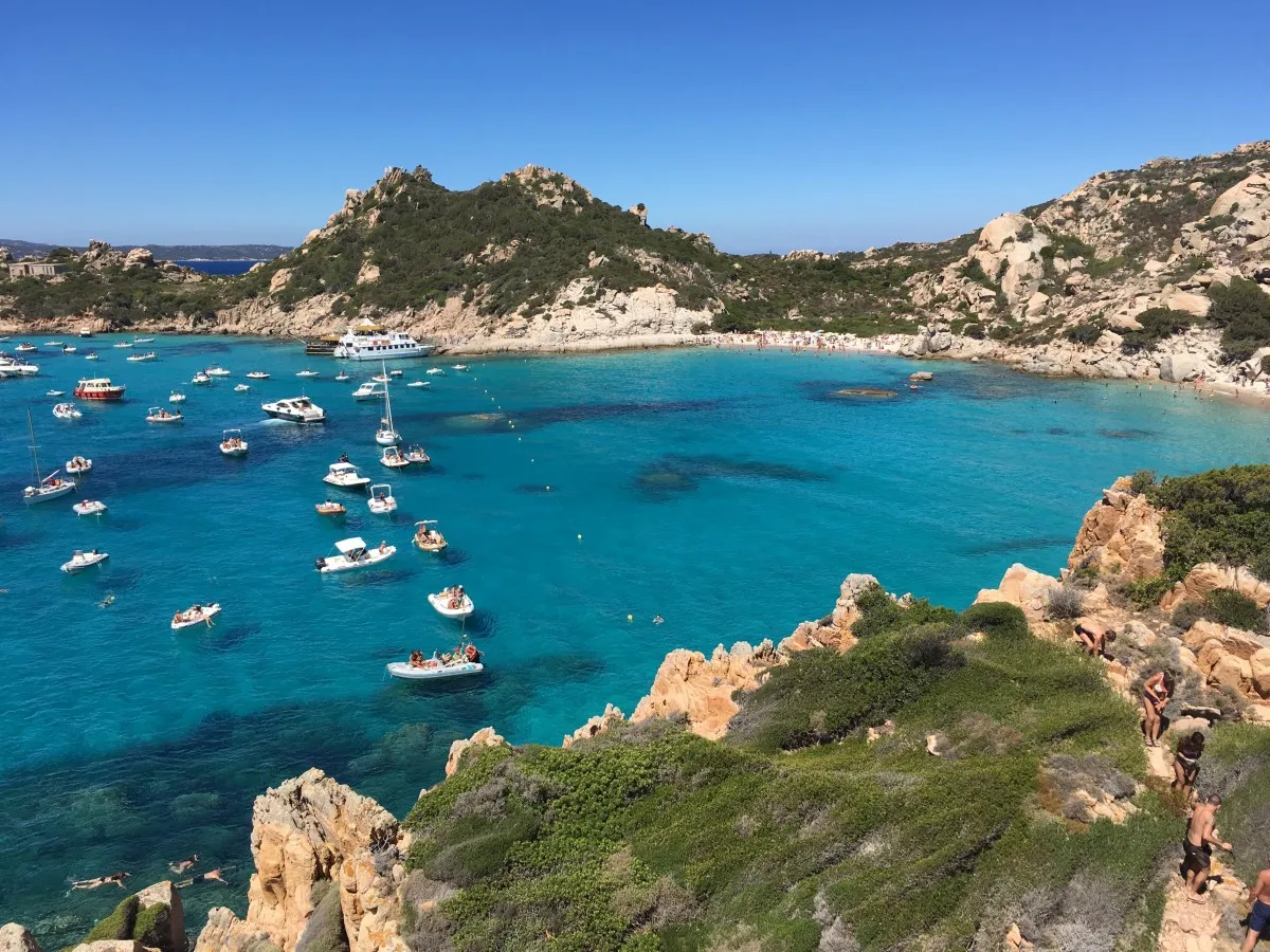 Panoramica de una de las playas de Cerdeña con las aguas color turquesa y barcos veleros