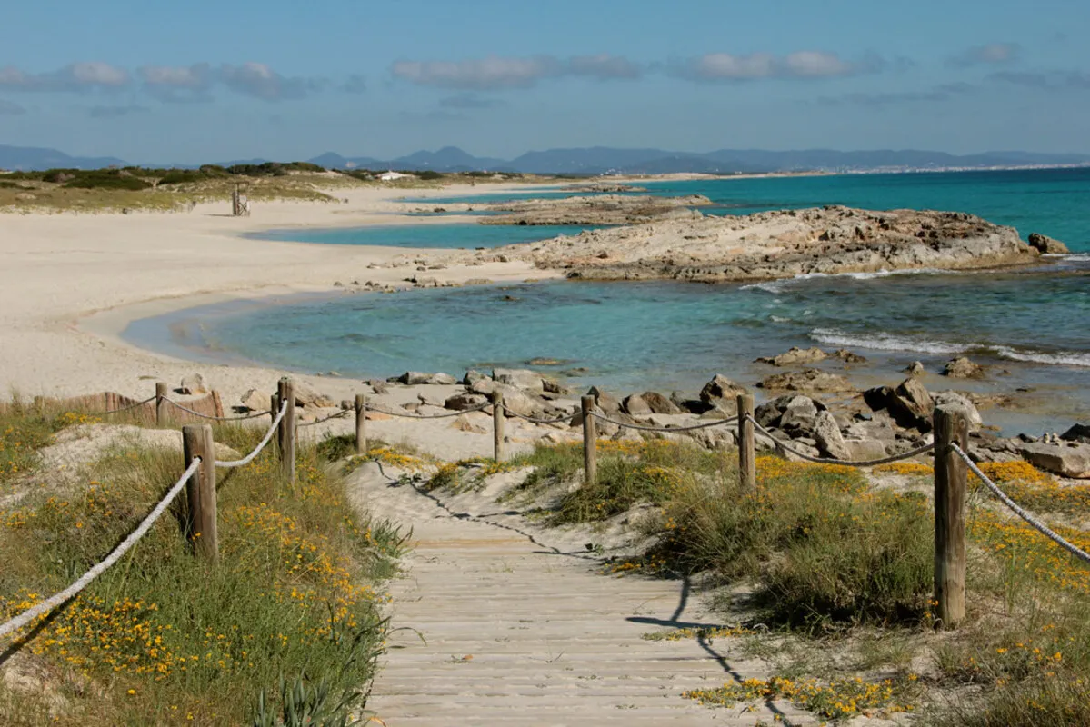 La entrada a la playa de arena blanca y agua turquesa a través de una pasarela de madera