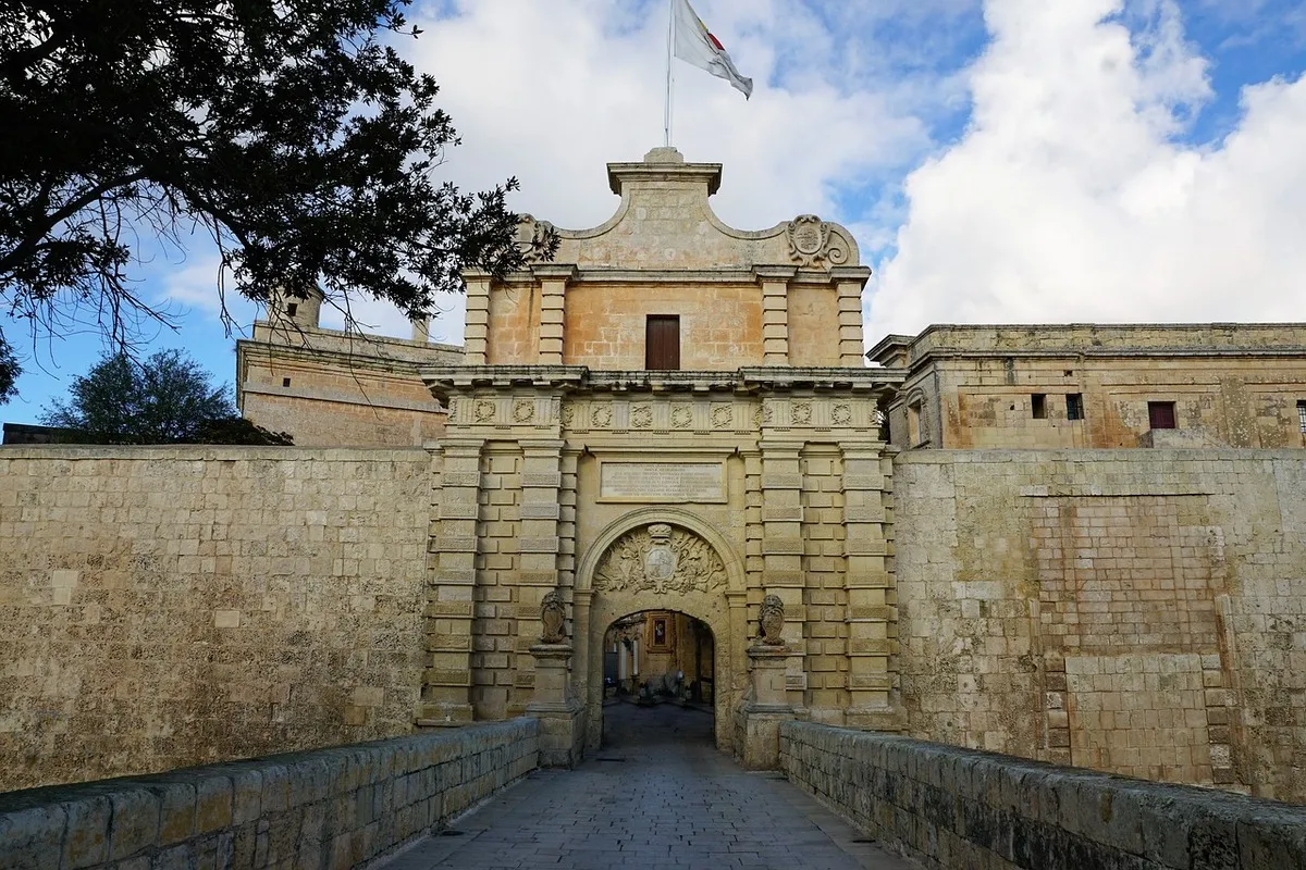 La entrada principal a la ciudad con un puente de piedra y un escudo tallado encima del arco de la entrda