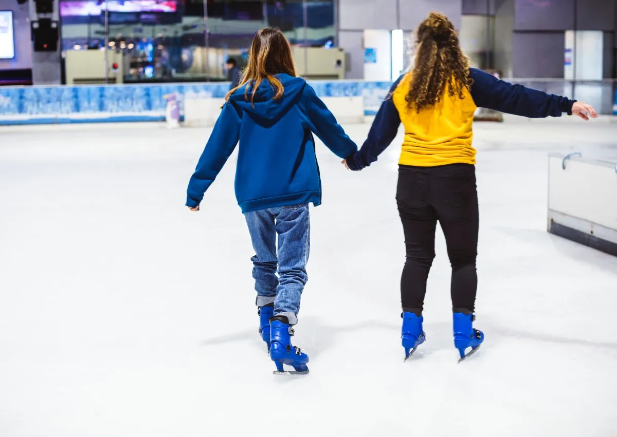 Dos chicas de espaldas haciendo patinaje sobre hielo
