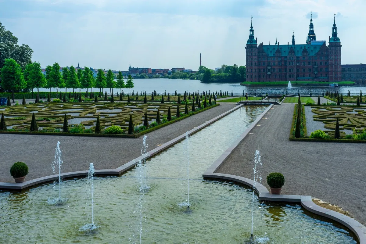 Una panoramica de los jardines estilo francés con una fuente y el castillo de fondo
