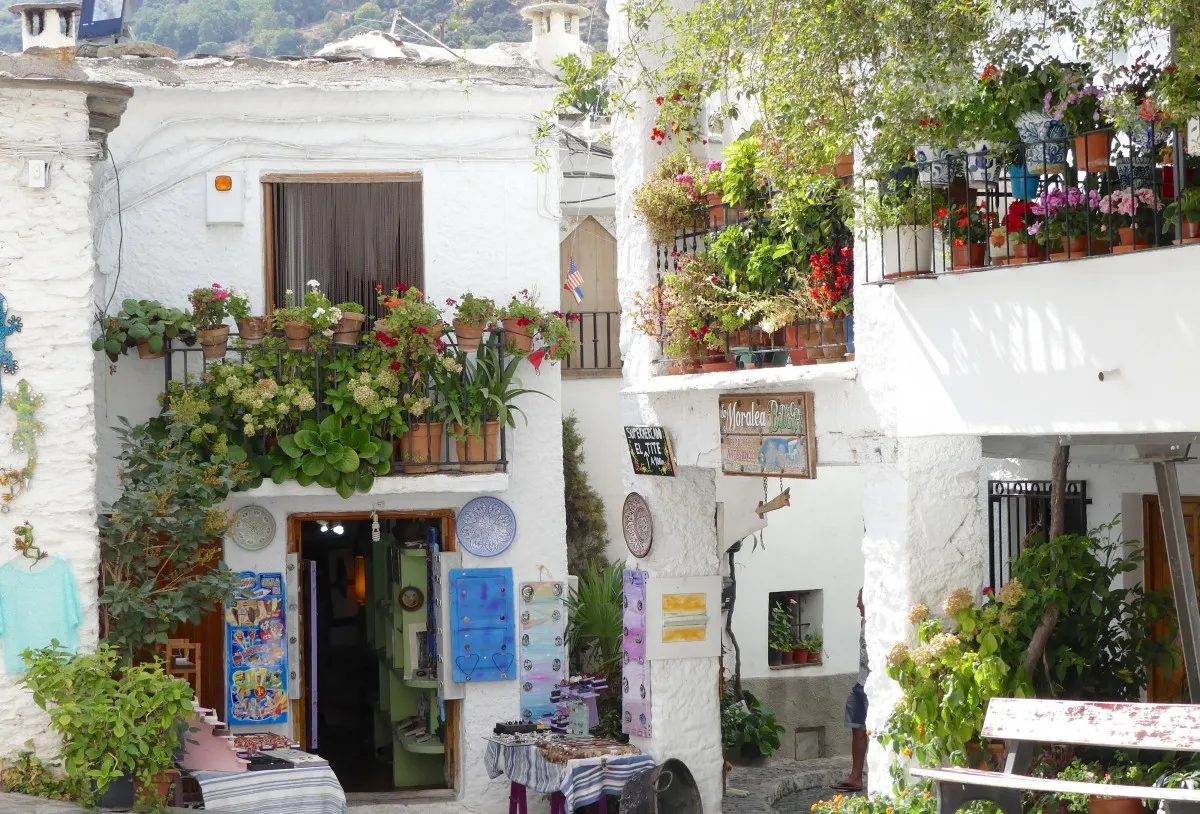 Casas blancas con balcones repletos de geranios y una pequeña tienda de souvenirs